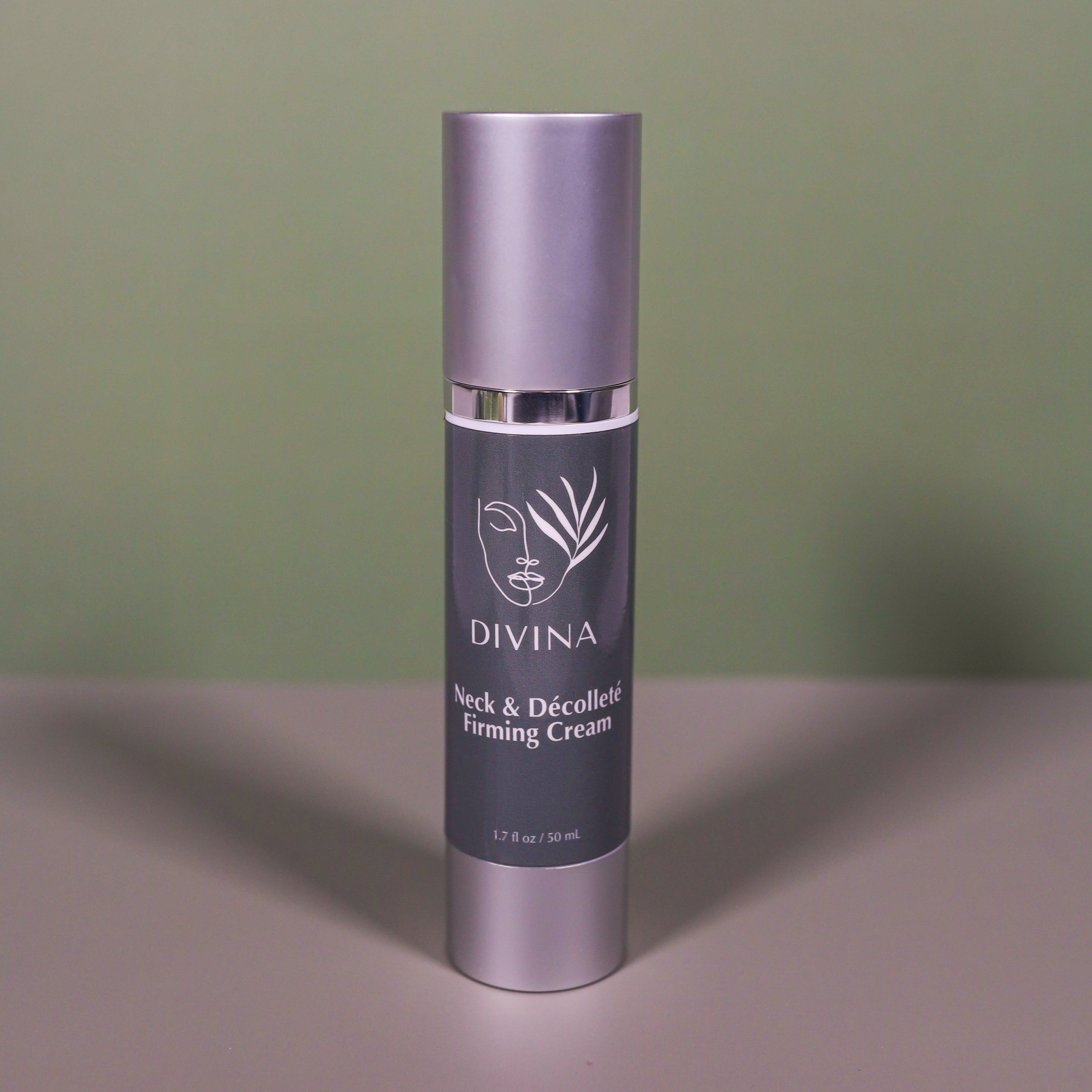 A bottle of Divina Neck & Décolleté Firming Cream with a gray label and silver cap rests on a flat surface against a muted green background. This luxurious cream is designed to firm the neck area and reduce wrinkles.