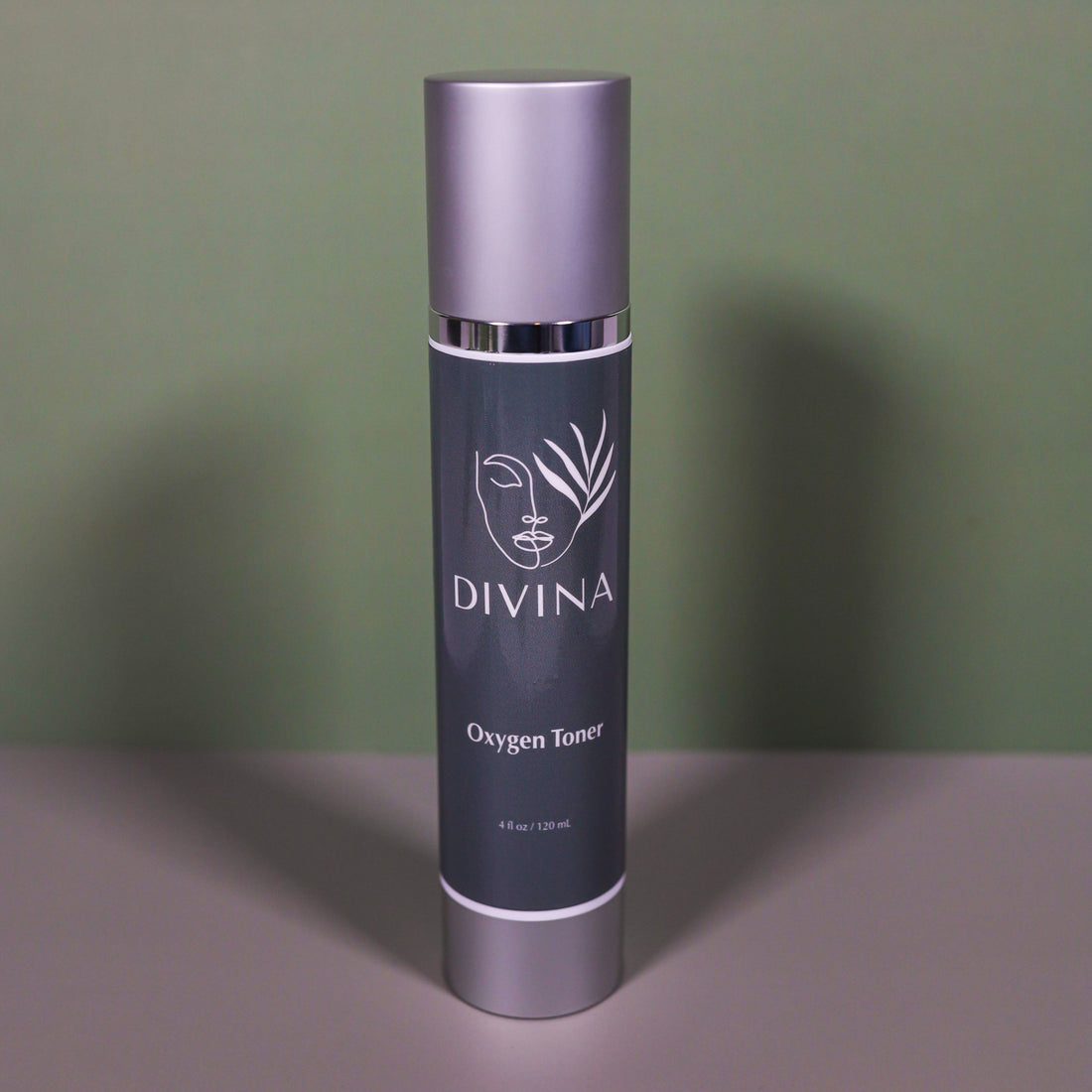 A silver and grey bottle of Divina Oxygen Toner stands upright on a flat surface against a muted green background, delivering intense hydration to support your skin barrier.