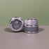 Two small silver jars of Divina’s Lip Nectar, a luxurious lip treatment, sit against a neutral background—one upright displaying the side label, the other tilted to spotlight the lid and Divina branding.